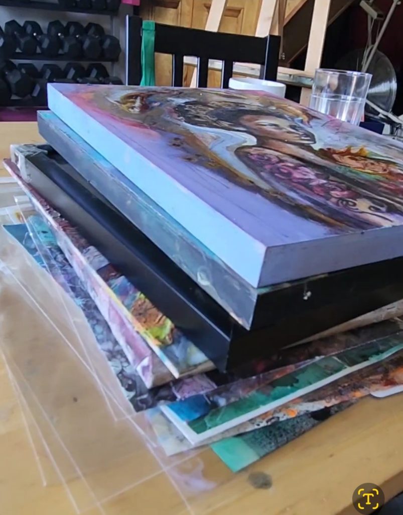 Art piled up on the table as Sara leger prepares her gallery for open studio tour