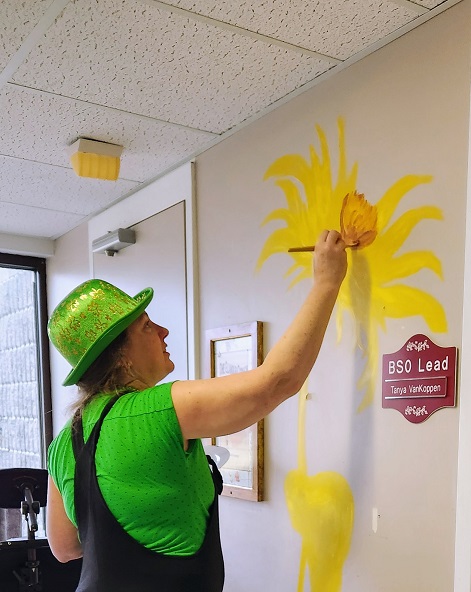 Mural of a sunflower by Sara Leger and Erynn at south glengarry long term care home. Erynn adding the first coat of paint .