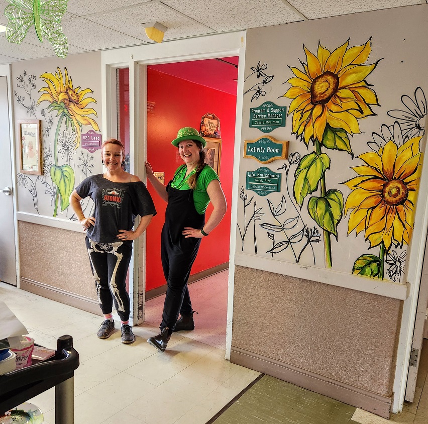 Sara Leger and Erynn standing in front of the mural of sunflowers in South Glengarry