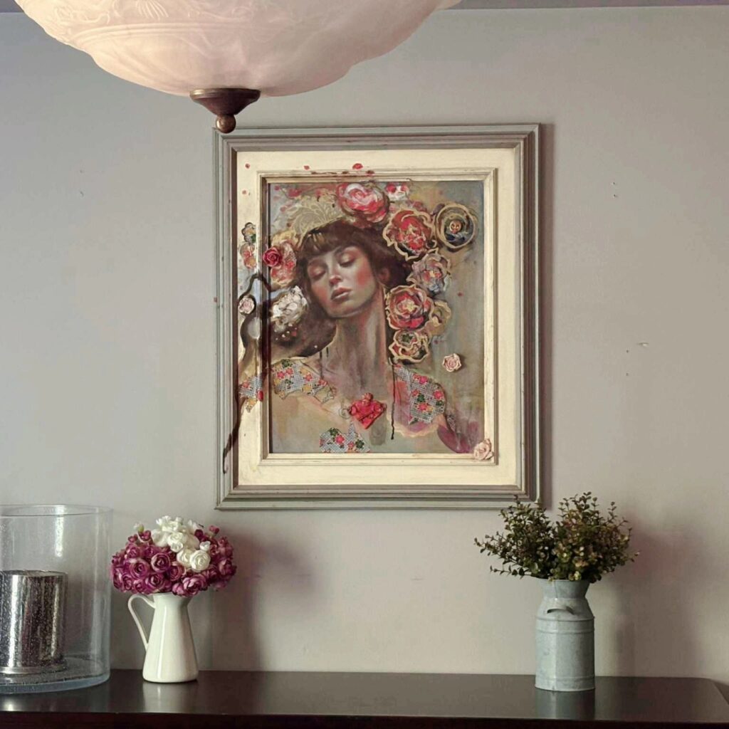 Mixed-media painting of a woman facing forward with a sculpted red Sacred Heart at her chest, with flowing hair covered in flowers