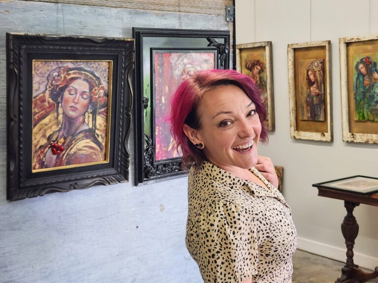 Sara Leger in her art studio gallery in front of her paintings