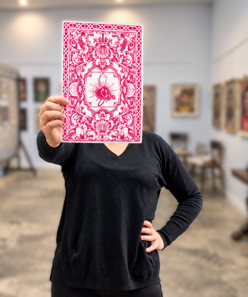 Sara Leger holding a print of her Sassy Bird fine art print showing the ornate back of the card